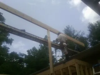 Carpenter setting a ridge beam over a new addition frame — Ice Dam Removal by Roofing Brothers in Rochert