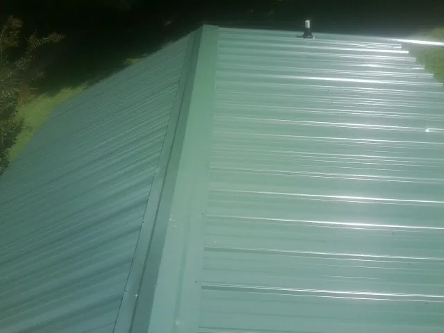 New green metal panels meeting at the ridge of a roof — Flat Roof Repair work by our crew in Rochert