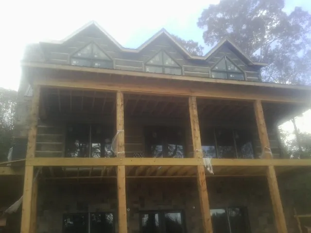 Dormers and porch framing on a large log home under construction — Roof Coating work by our crew in Rochert