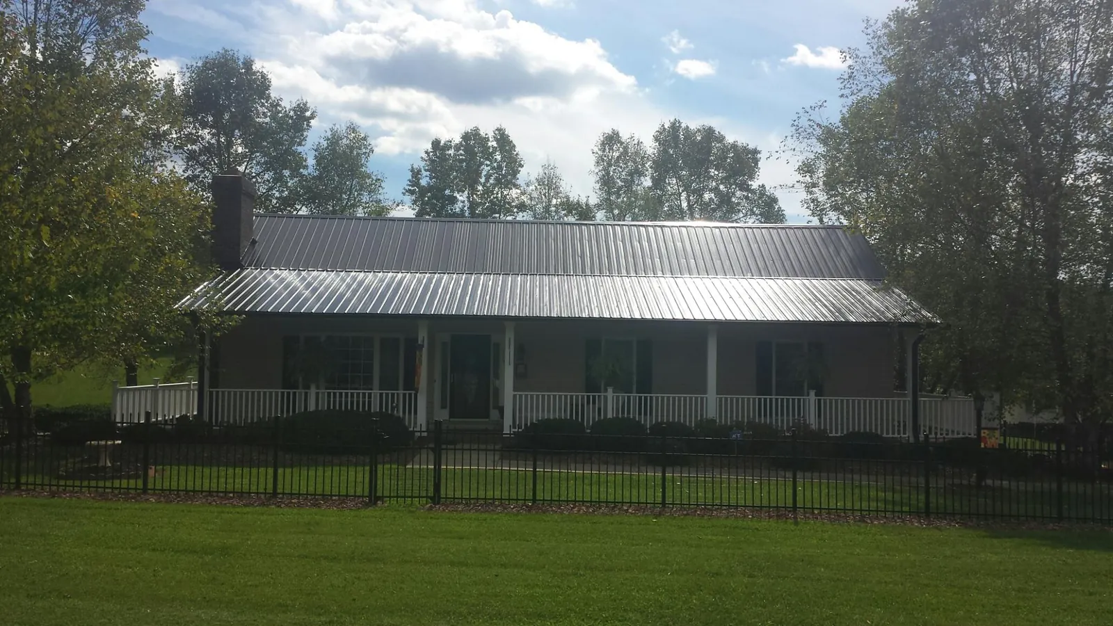 Gray metal roof on a brick ranch with a full width front porch — Gutter Guard Installation work by our crew in Rochert