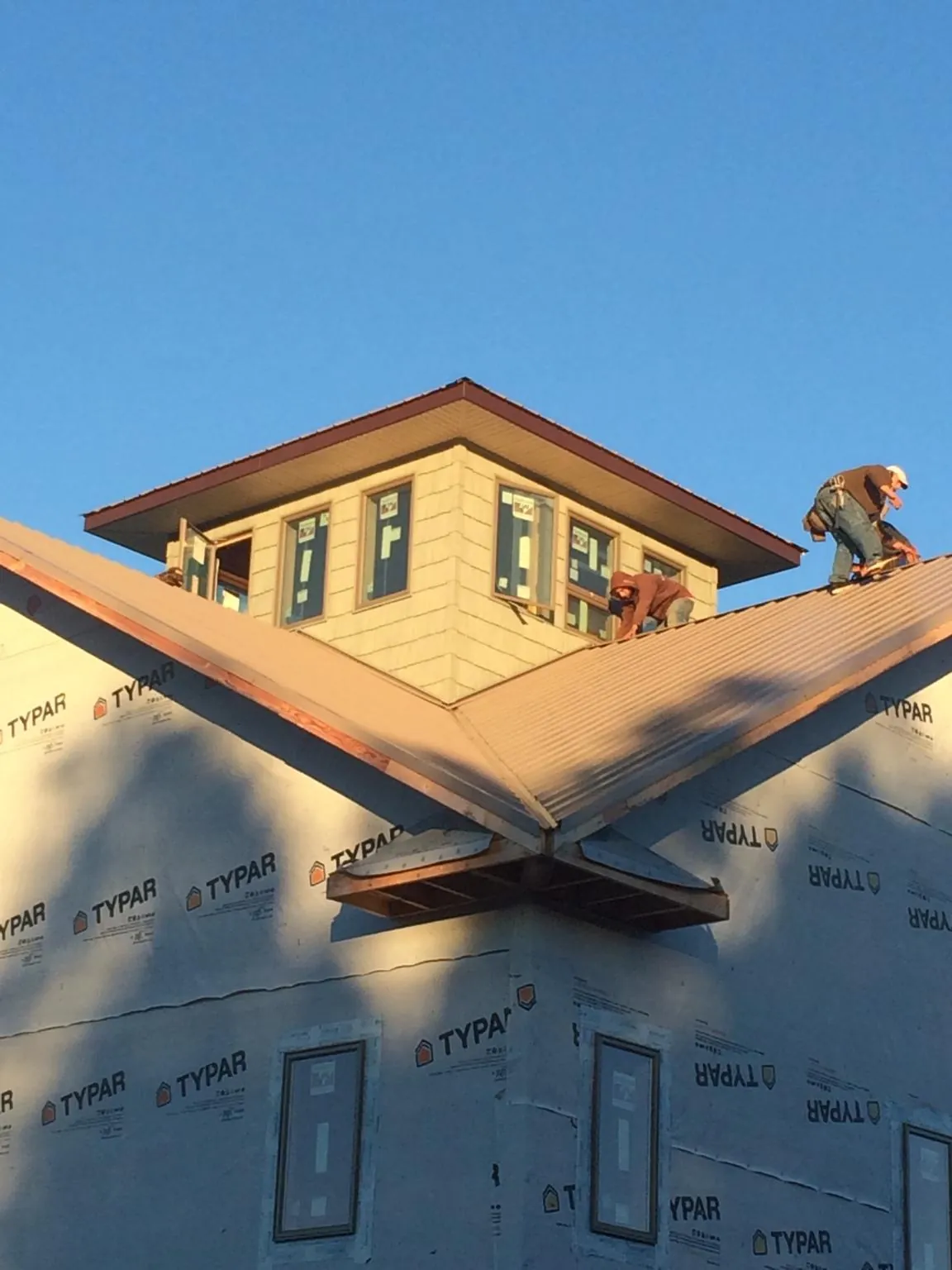 Roofers working around a rooftop cupola on a new metal roof at sunset — Roof Waterproofing in Rochert by Roofing Brothers